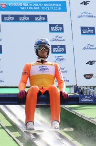 Maciej Kot w żółtym plastronie lidera FIS Grand Prix na belce startowej